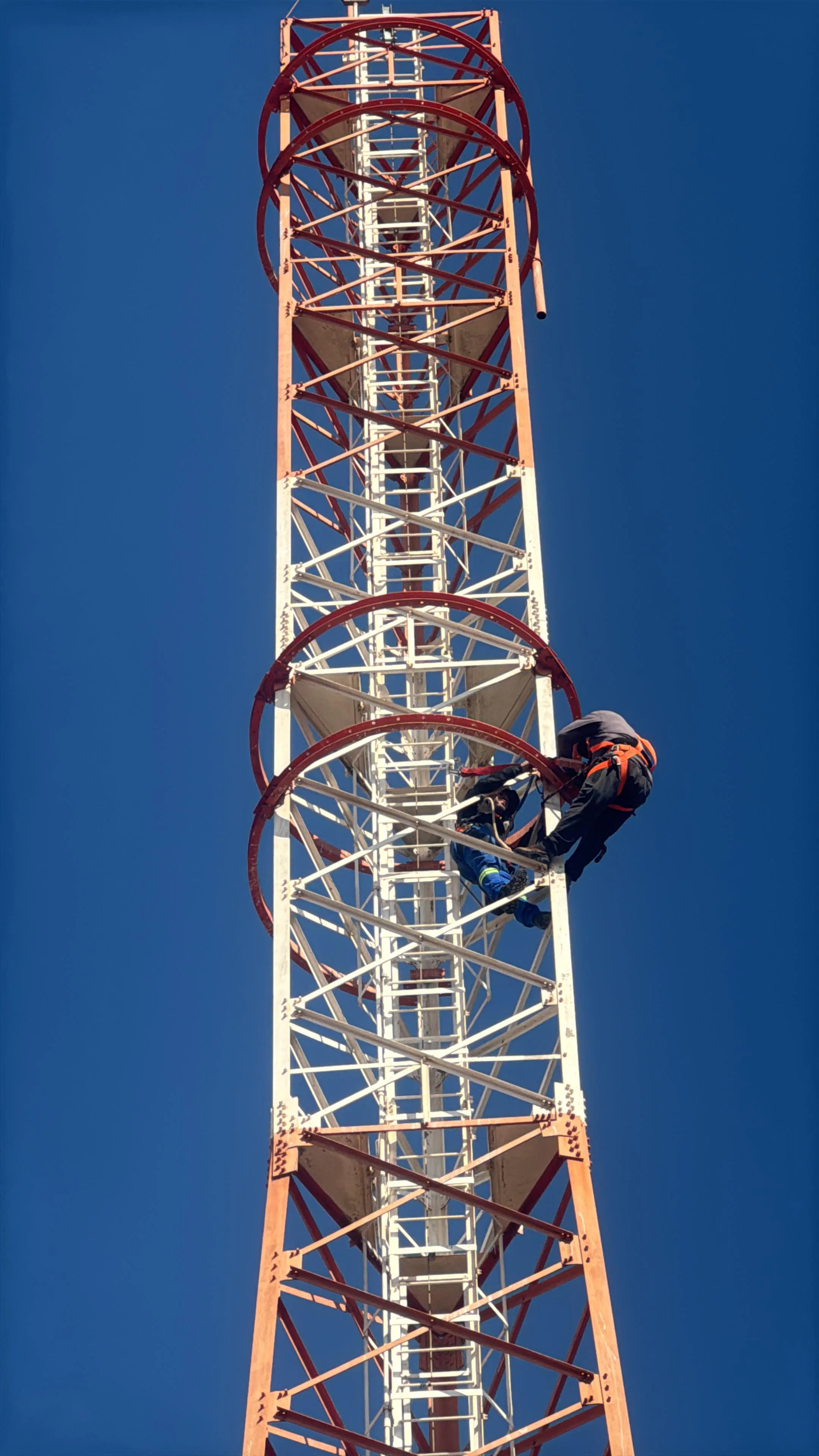 Técnicos trabalhando na estrutura metálica de uma torre de telecom