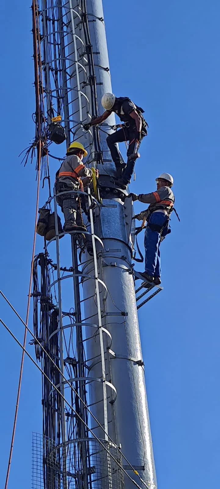 Equipe técnica executando manutenção em altura em torre de telecom